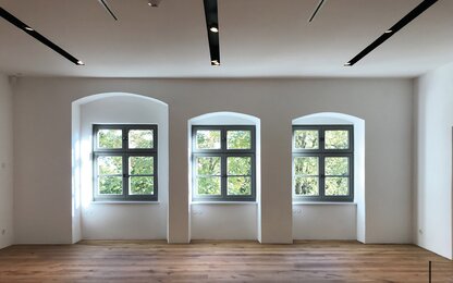Heller Raum mit drei Fenstern und Holzfußboden