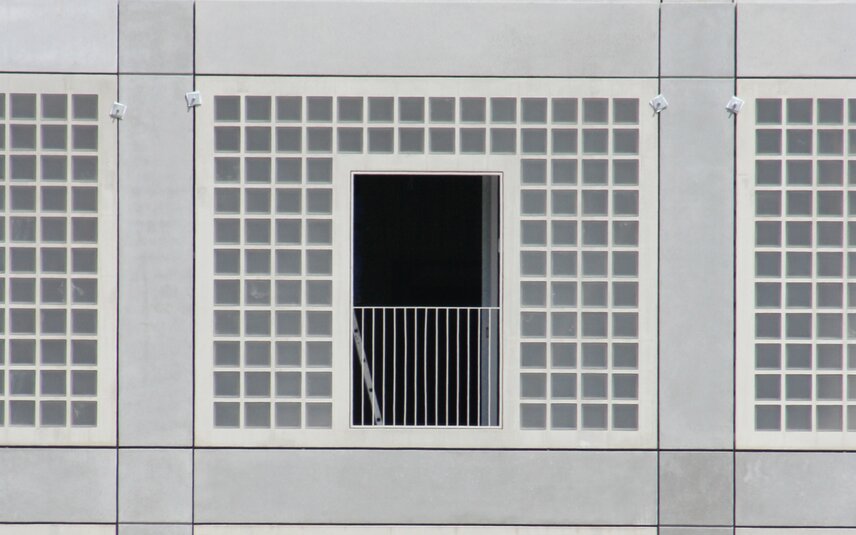 Graue Fassadenfront mit Balkon und Raster