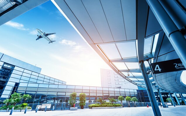 Aircraft on approach over a modern airport terminal with large-area glazing façades